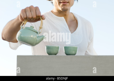 Man holding teapot, recadré, mid section Banque D'Images