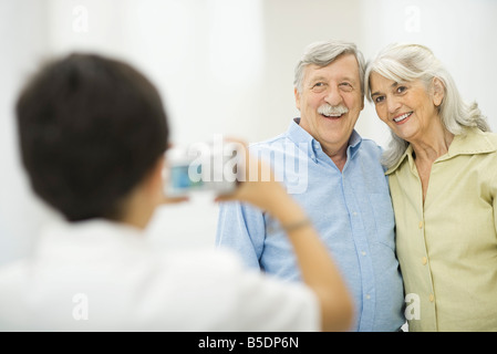 Petit-fils de prendre une photographie des grands-parents avec appareil photo numérique Banque D'Images