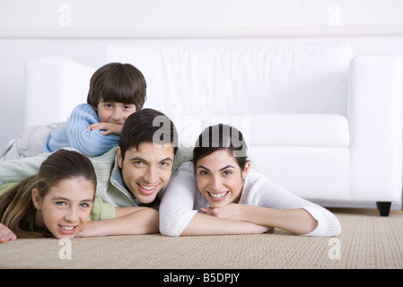 Family lying together sur marbre, fils étendu sur son père est de retour, tous les smiling at camera Banque D'Images