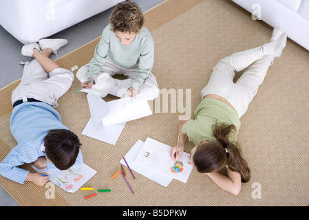 Trois enfants coloriages sur le plancher, high angle view Banque D'Images