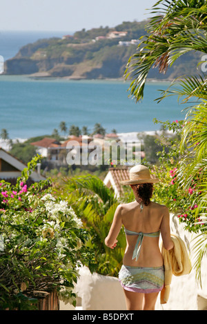 Femme avec chapeau de soleil à pied jusqu'à la plage jardin tropical luxuriant d'une journée ensoleillée à San Juan del Sur Nicaragua côte du Pacifique Banque D'Images