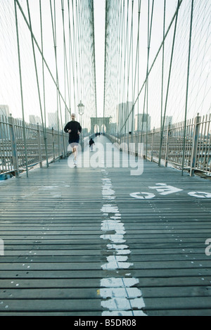 Jogger sur passerelle piétonne du pont de Brooklyn, dans la ville de New York, Manhattan skyline à distance Banque D'Images