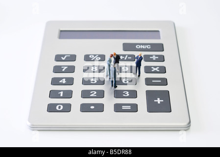 Businessmen standing miniature sur calculatrice Banque D'Images