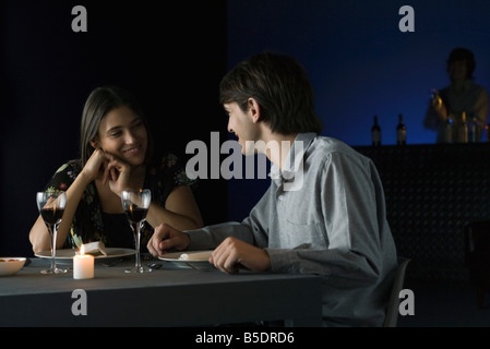 Couple having conversation autour d'un dîner au restaurant, smiling at each other Banque D'Images