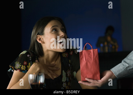 Femme étant présenté avec don, à la recherche jusqu'à l'étonnement au donateur Banque D'Images