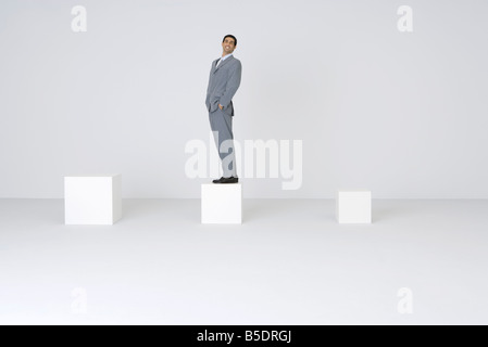 Businessman standing on bloc avec les mains dans les poches, smiling at camera Banque D'Images