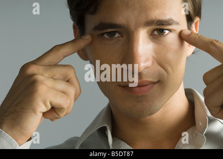 Homme pointant à yeux, looking at camera, close-up Banque D'Images