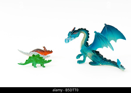 Dragon jouet face à trois petits dinosaures jouets Banque D'Images