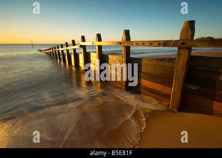 Les vagues se précipiter à travers les défenses maritimes en bois sur le front de mer à Dawlsih dawn Dawlish Devon UK Banque D'Images