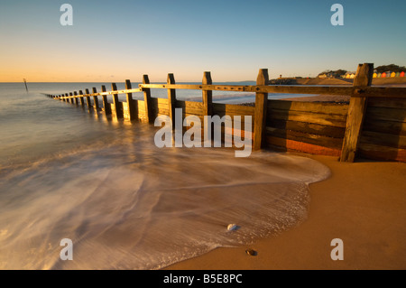 Les vagues se précipiter à travers les défenses maritimes en bois sur le front de mer à l'aube Dawlish Dawlish Devon UK Banque D'Images