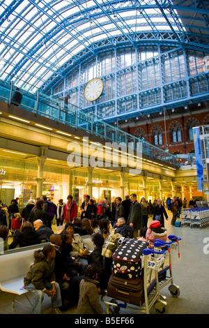 , Londres St Pancras Gare Ferroviaire famille Afro Antillais noir sur banc avec assurance sur les chariots pour le train d'attente Banque D'Images