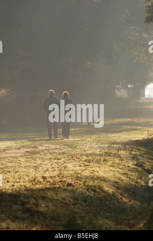 Couple marche main dans la main dans la campagne du Cheshire avec une alimentation des daims dans l'arrière-plan Banque D'Images