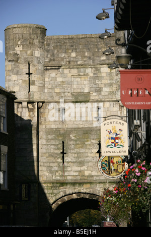 Ville de York, en Angleterre. Enseignes et aux paniers de fleurs suspendus en haute Petergate, avec Bar Bootham gateway dans l'arrière-plan. Banque D'Images