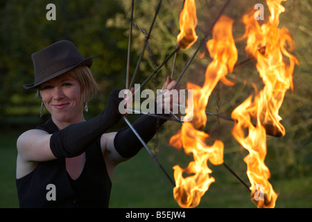 Femme firepoise fire dance performance artist wearing hat holding fire fans Banque D'Images