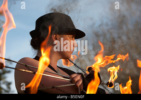 Femme firepoise fire dance performance artist wearing hat holding fire fans Banque D'Images