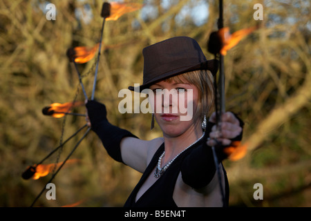 Femme firepoise fire dance performance artist wearing hat holding fire fans Banque D'Images