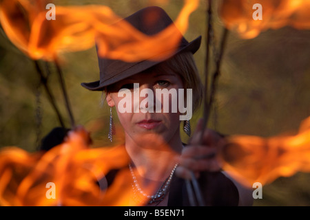 Femme firepoise fire dance performance artist wearing hat holding fire fans Banque D'Images