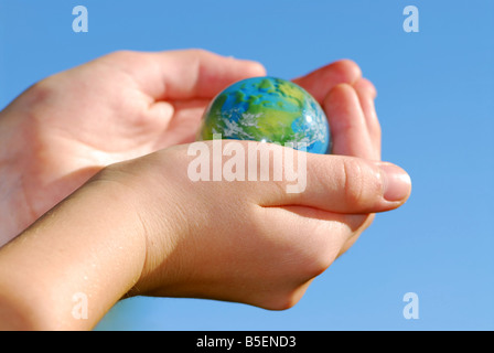 Enfant tenant un globe dans la main sur fond bleu Banque D'Images