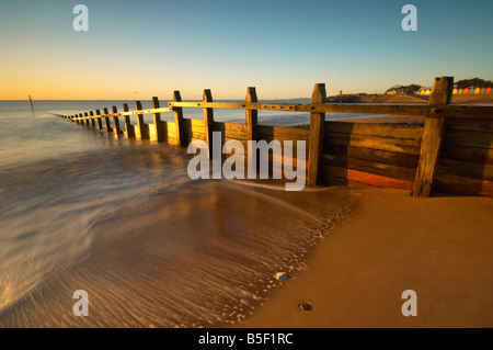 Les vagues se précipiter à travers les défenses maritimes en bois sur le front de mer à l'aube Dawlish Dawlish Devon UK Banque D'Images