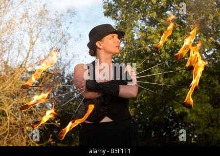 Femme firepoise fire dance performance artist wearing hat holding fire fans Banque D'Images