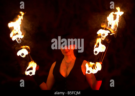 Femme firepoise fire dance performance artist wearing hat holding fire fans la nuit effectuer Banque D'Images