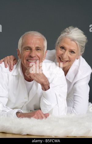 Senior couple allongé sur un tapis de fourrure Banque D'Images