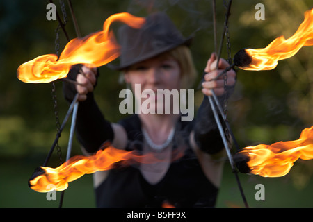 Femme firepoise fire dance performance artist wearing hat holding fire fans Banque D'Images