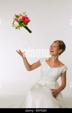 Jeune mariée bouquet de mariée jetant, rire Banque D'Images