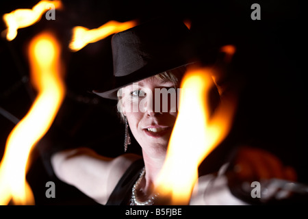 Femme firepoise fire dance performance artist wearing hat holding fire fans la nuit effectuer Banque D'Images