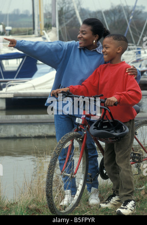 Femme noire et son fils sur des vélos par Harbour Banque D'Images