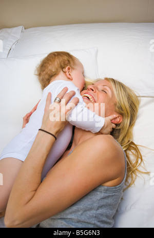30 ans, mère et enfant de 10 mois embrassant sur un lit Banque D'Images