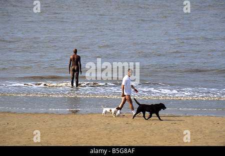 Antony Gormley Exposition "Un autre endroit", avec passant et chien, Crosby Beach, près de Liverpool, Angleterre 2005 Banque D'Images