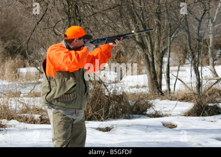 Un chasseur de faisan son arme de tir tout en tenant un oiseau mort et la shell éjecté en l'air. Banque D'Images