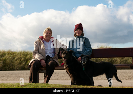 Les jeunes et les dames âgées assis comme un couple assis sur le siège de la promenade par la plage d''Aberdeen Scotland UK Banque D'Images
