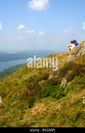 Jeune couple assis près de haut de Gummer's comment admirer la vue sur le lac Windermere, Lake District Banque D'Images