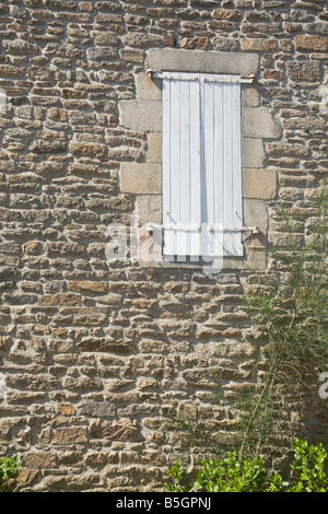Fenêtre dans mur en pierre avec des volets fermés Banque D'Images
