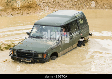 Land Rover Discovery la conduite hors route à travers de profondeur de l'eau boueuse au Royaume-Uni Banque D'Images