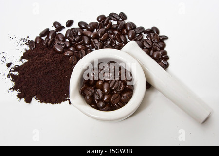 Un mortier remplis de grains de café gourmet fraîchement torréfié avec des grains de café et meuler à côté isolé sur fond blanc Banque D'Images