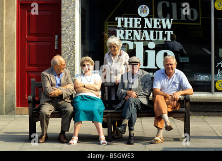 Groupe de retraités sur le banc de la rue à discuter ensemble - pays de Galles, Royaume-Uni. Banque D'Images