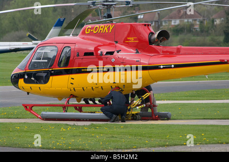 Réparation mécanique travaille sur un hélicoptère rouge et jaune G teabua orky aérodrome Redhill Surrey UK Helicopters Banque D'Images