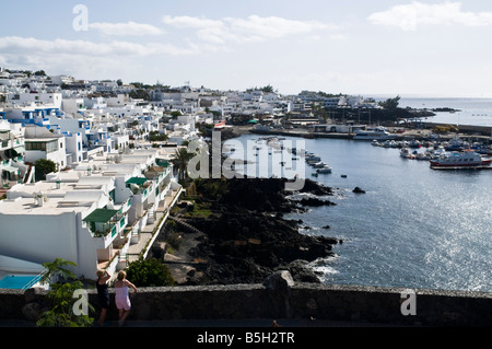 Dh PUERTO DEL CARMEN LANZAROTE Tourist couple femmes vacanciers donnent sur le vieux port et appartements Banque D'Images