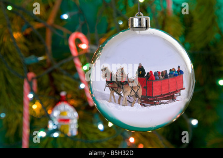 Une carriole dans la neige profonde à l'époque de Noël reflète dans un ornement d'arbre de Noël avec des cannes de bonbon et de lumières Banque D'Images