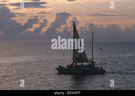 Voilier au coucher du soleil au large de la côte de Negril Jamaïque Banque D'Images