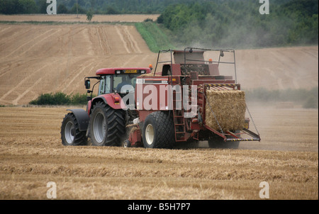 Un tracteur fait hay bails sur les régions rurales et entre Clare et Cavendish à Suffolk Banque D'Images