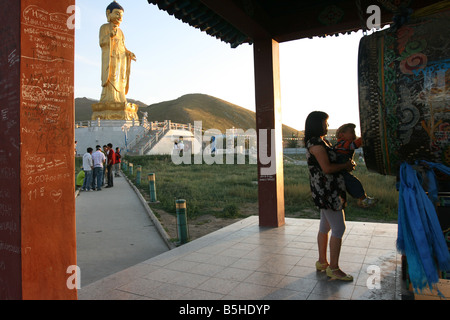 Soins Femme un garçon sur sa main en face de statue de Bouddha. Oulan Bator. La Mongolie Banque D'Images