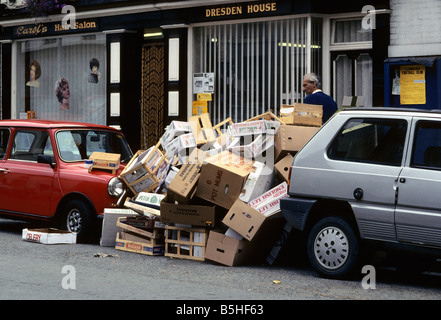 Les ordures dans la rue centre ville de empilés entre les voitures stationnées, Powys, Wales, UK. Banque D'Images