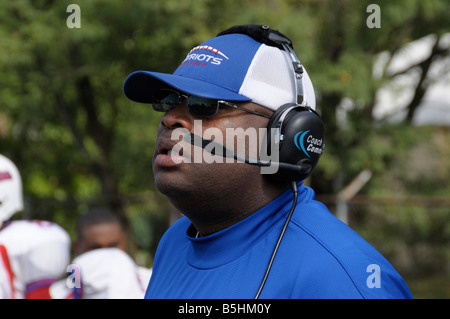Coach en donnant des instructions sur un casque au cours d'un match de football à l'école secondaire agréable siège Banque D'Images