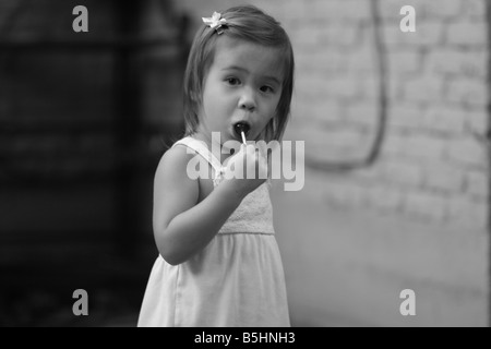 Un 2-year-old girl sucks sur une sucette dans sa bouche. Banque D'Images