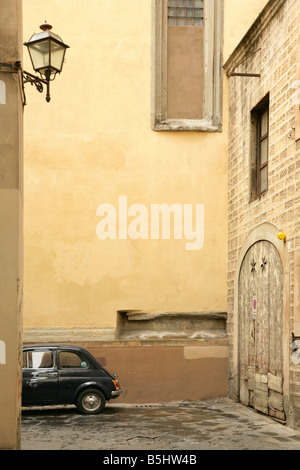 Fiat 500 noire ancienne voiture garée en bas petite rue étroite à Florence, Italie. Banque D'Images