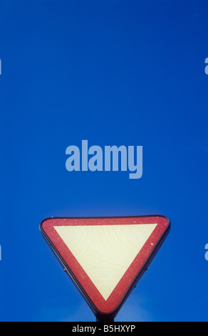 Rouge et blanc vide triangulaire à l'envers à l'avance de donner roadsign céder ou ligne d'arrêt avec ciel bleu Banque D'Images